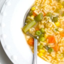 A close up of Alphabet Soup in a bowl with a spoon.