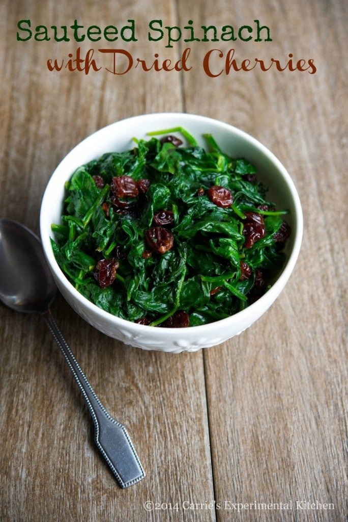A bowl of spinach with dried cherries.