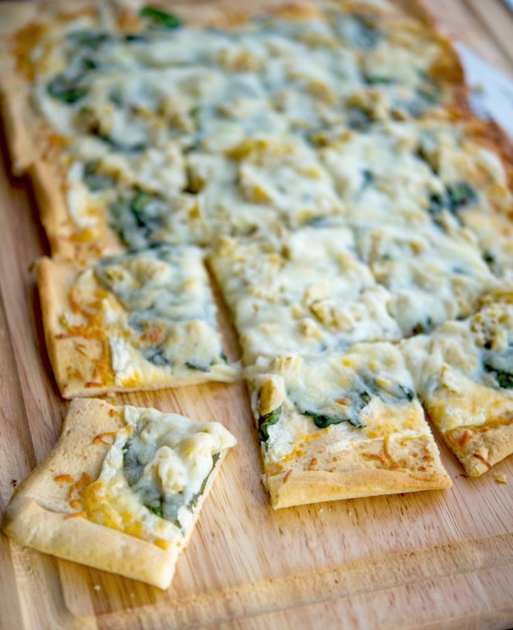 A slice of pizza sitting on top of a wooden cutting board, Spinach & Artichoke Flatbread 