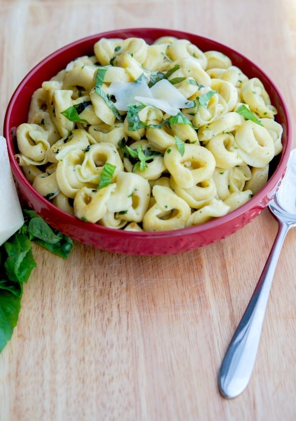 A bowl of food on a wooden table, with tortellini pasta