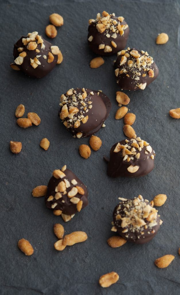 Dark Chocolate Nutter Butter Truffles in a row on slate. 