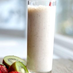 A close up of a glass of Strawberry, kiwi and banana smoothie with a straw