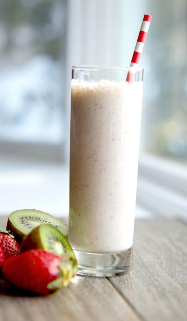 A close up of a glass of Strawberry, kiwi and banana smoothie with a straw