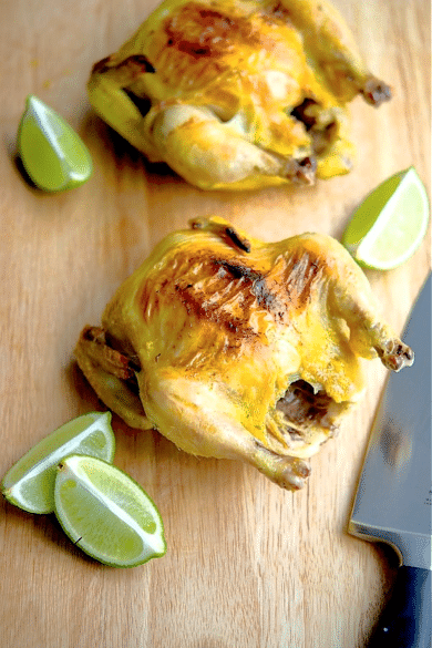 two cornish hens on a cutting board with limes