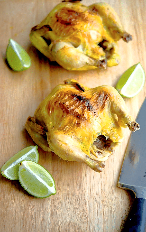 two cornish hens on a cutting board with limes