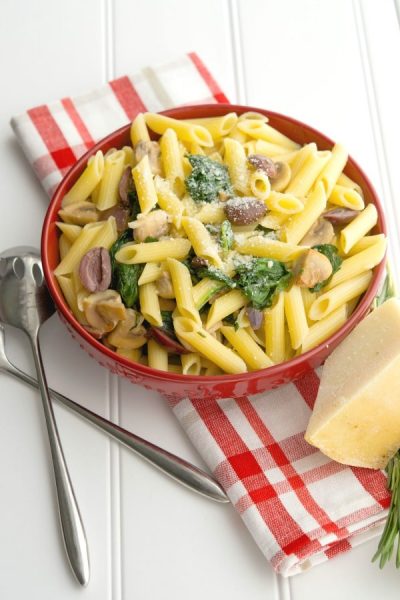 A bowl of food on a plate, with Pasta and Spinach