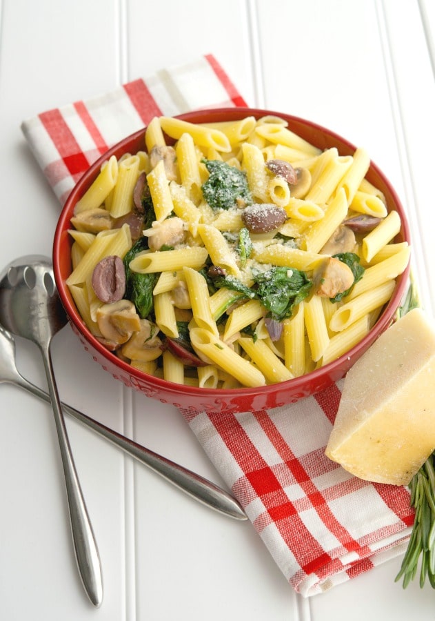 A bowl of food on a plate, with Pasta and Spinach