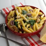 A bowl of penne pasta with spinach and mushrooms
