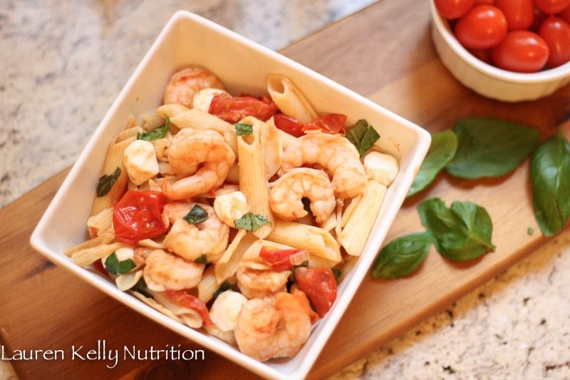 A bowl filled with different types of food on a table, with Salad and Pasta