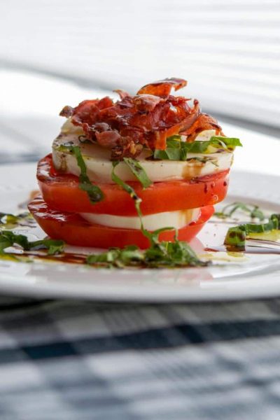 Caprese Stacks made with fresh mozzarella, Heirloom tomatoes and Italian prosciutto then topped with aged balsamic vinegar.