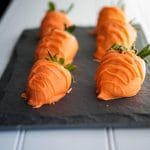 Chocolate covered carrot strawberries on a slate board.