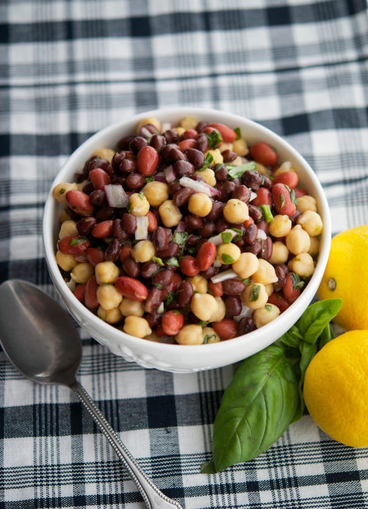 A bowl of Lemon-Basil Three Bean Salad on table with a spoon