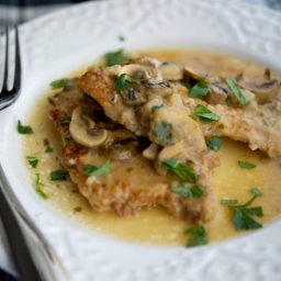 a close up of pork marsala with a fork