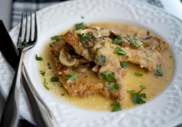 a close up of pork marsala with a fork