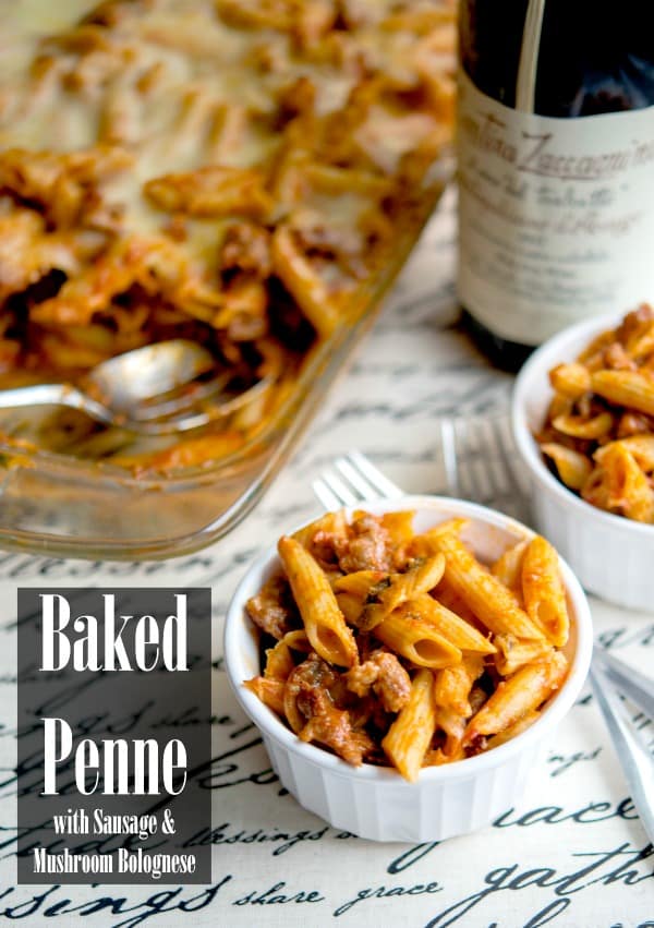 A bowl of baked penne with sausage and mushroom bolognese with a fork