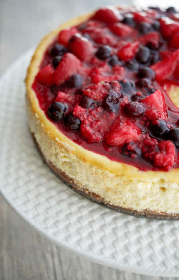 A close up of Vanilla Bean Cheesecake with mixed berries on top. 