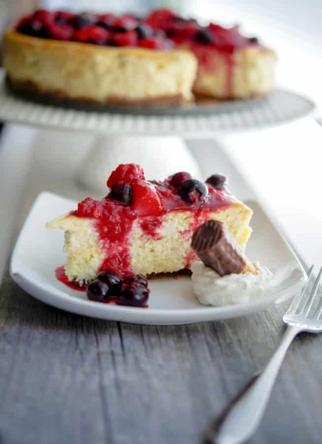 This Vanilla Bean Cheesecake made with cream cheese, Madagascar vanilla extract, vanilla beans, eggs, and sugar; then topped with a compote of fresh raspberries, strawberries and blueberries.