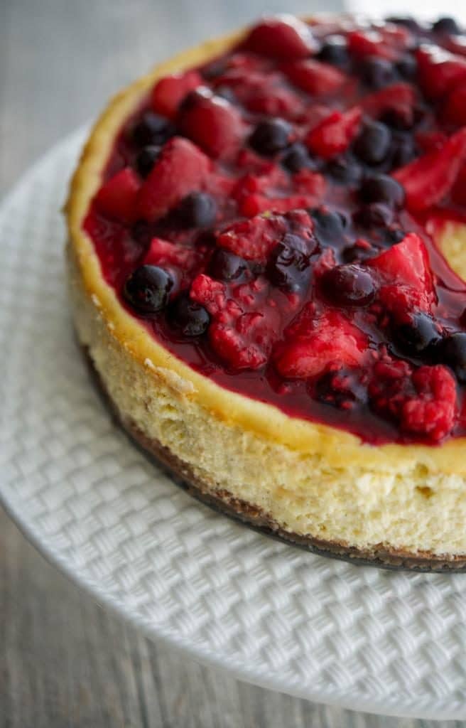 A close up Vanilla Bean Cheesecake with Mixed Berry Compote