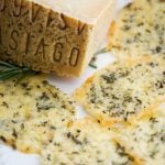 A piece asiago cheese with cheese crisps on a plate.