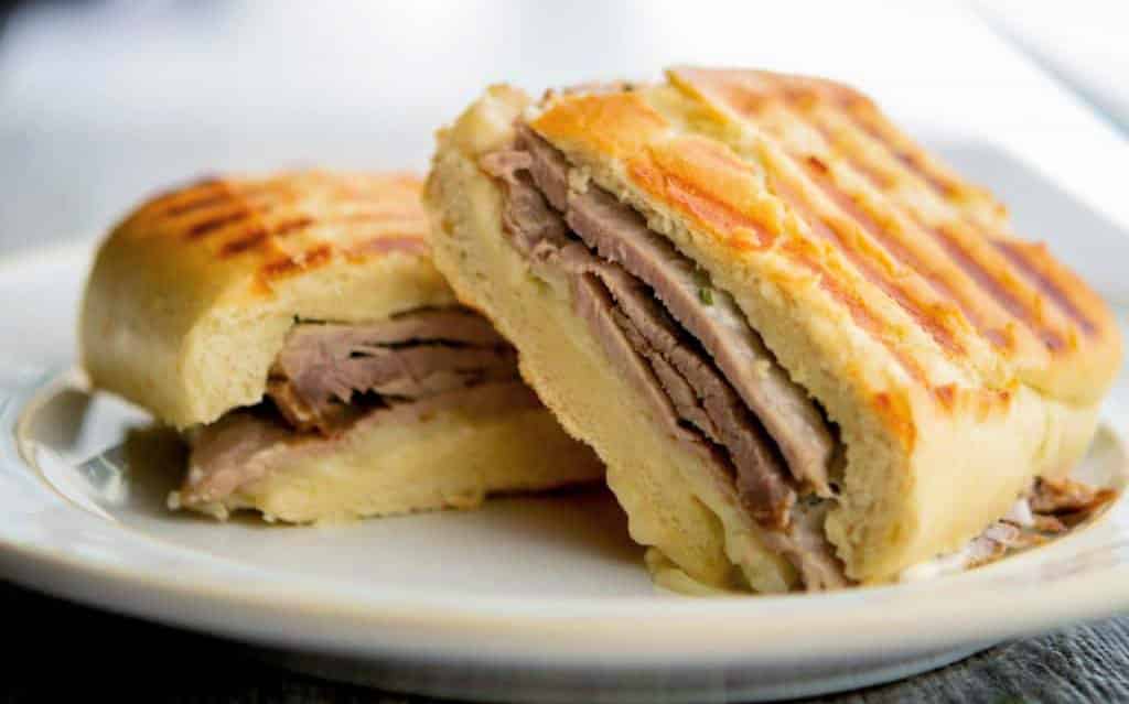 A sandwich cut in half on a plate, with Roast beef