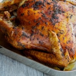 A close up of a whole roasted turkey in a pan. 