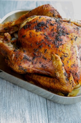 A close up of a whole roasted turkey in a pan. 