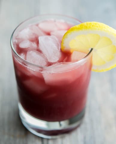 A glass of Italian Sangria with ice and a lemon garnish. 