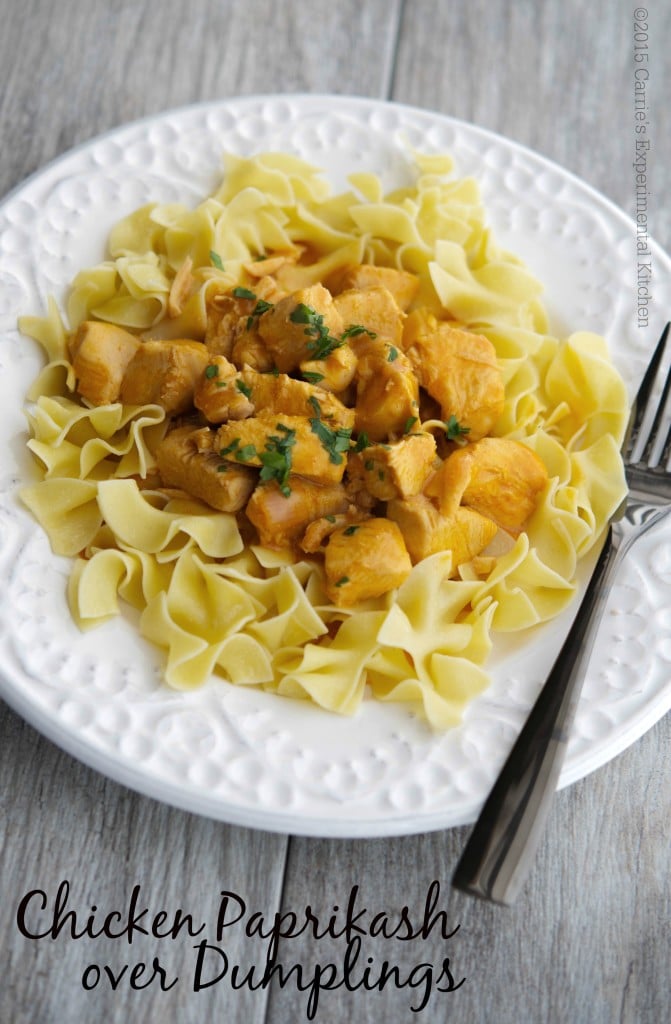 Chicken Paprikash over egg noodles on a white plate with a fork.