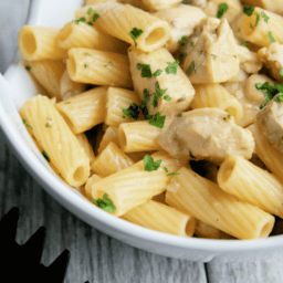 A close up of pasta and chicken in a white bowl