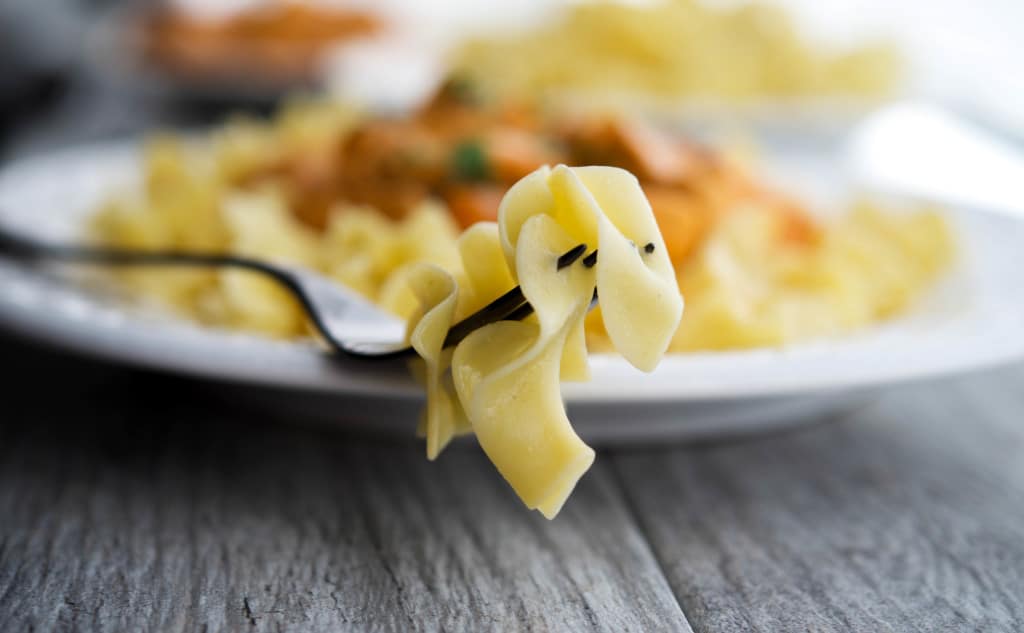 A close up of egg noodles on a fork.