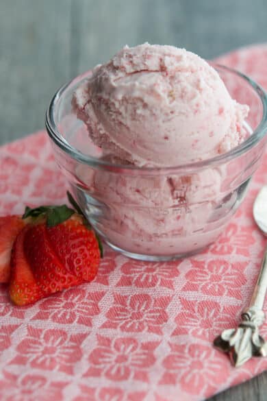Two scoops of homemade strawberry ice cream in a glass dish.
