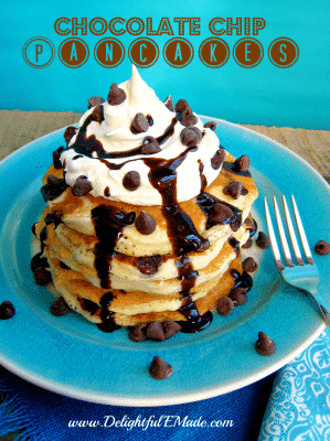 A plate of chocolate chip pancakes topped with whipped cream. 