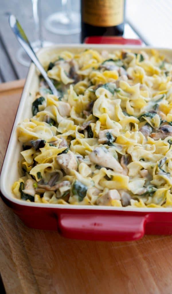 Creamy Chicken, spinach and mushroom casserole in a red casserole dish 