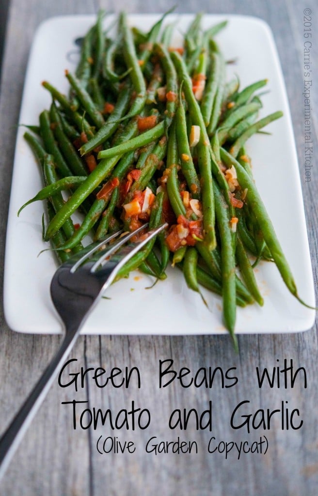 A plate of green beans with tomatoes and garlic. 