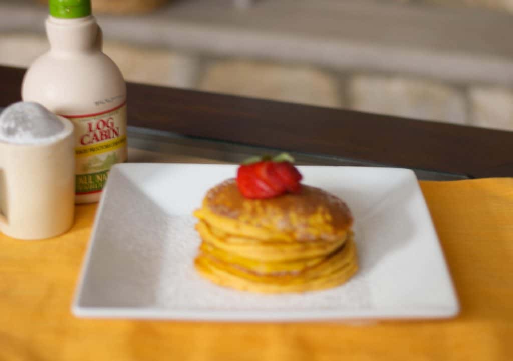 Pumpkin Pancakes on a plate topped with strawberries. 