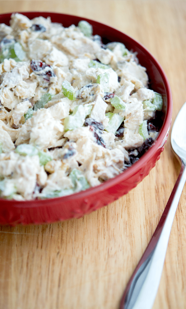 a red bowl of chicken salad with a spoon