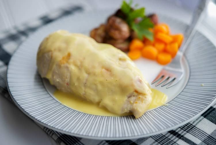Chicken on a plate topped with bernaise sauce. 