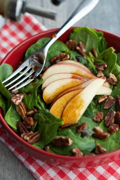 Spinach Salad with Apples and Pecans in a red bowl.