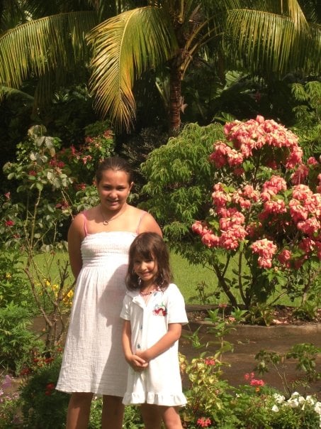 Two girls standing in front flowers