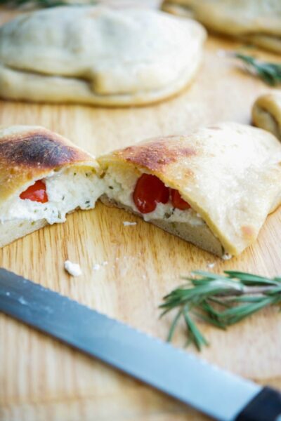 open calzone with cheese and tomatoes on a wooden board