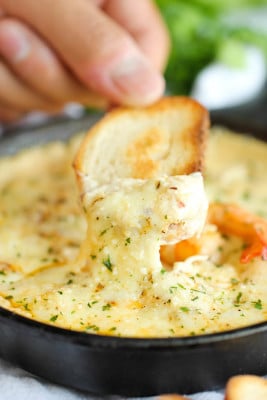 A close up of a person holding a piece of food, with Shrimp and Seafood