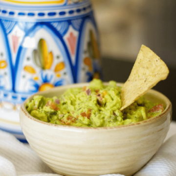 A bowl of food on a table, with Guacamole and Avocado