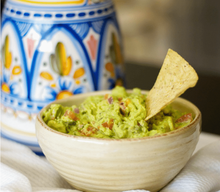A bowl of food on a table, with Guacamole and Avocado