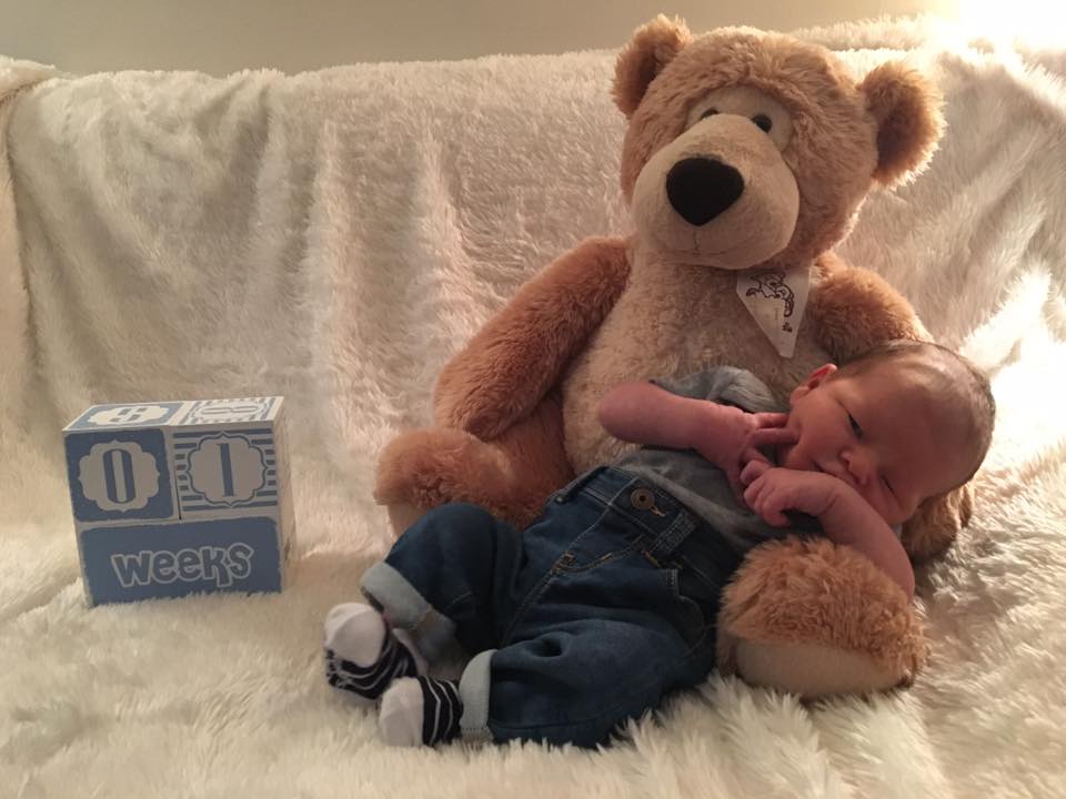 A large brown teddy bear sitting on top of a bed