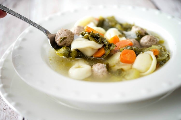 Tortellini Escarole Soup in a white bowl on a spoon