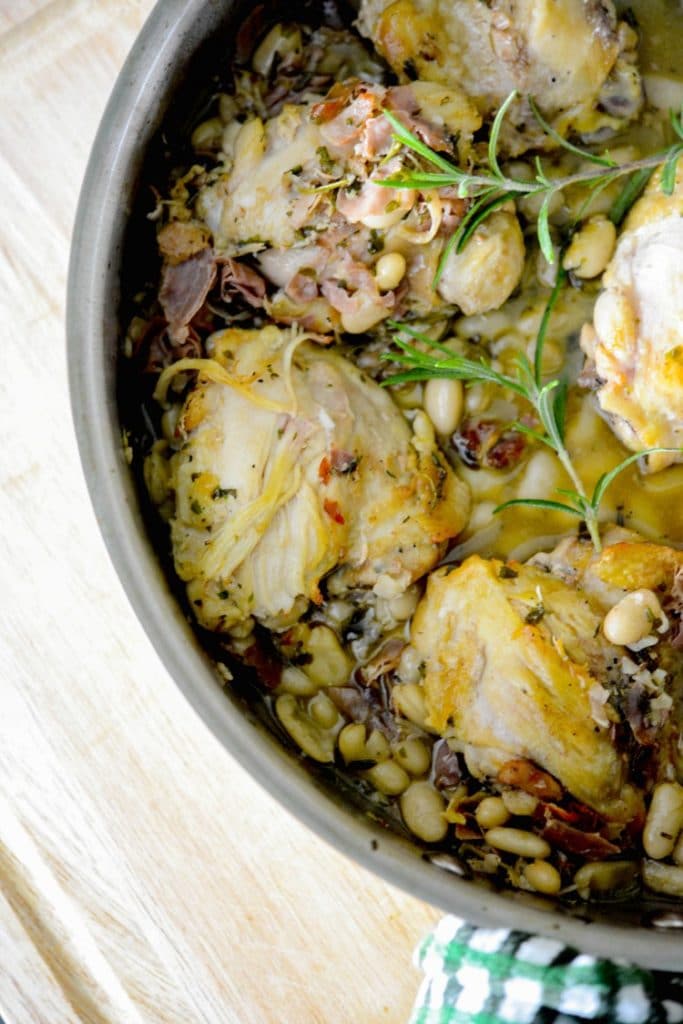 A close up of Chicken Thighs with Prosciutto, Rosemary and White Beans in a skillet. 