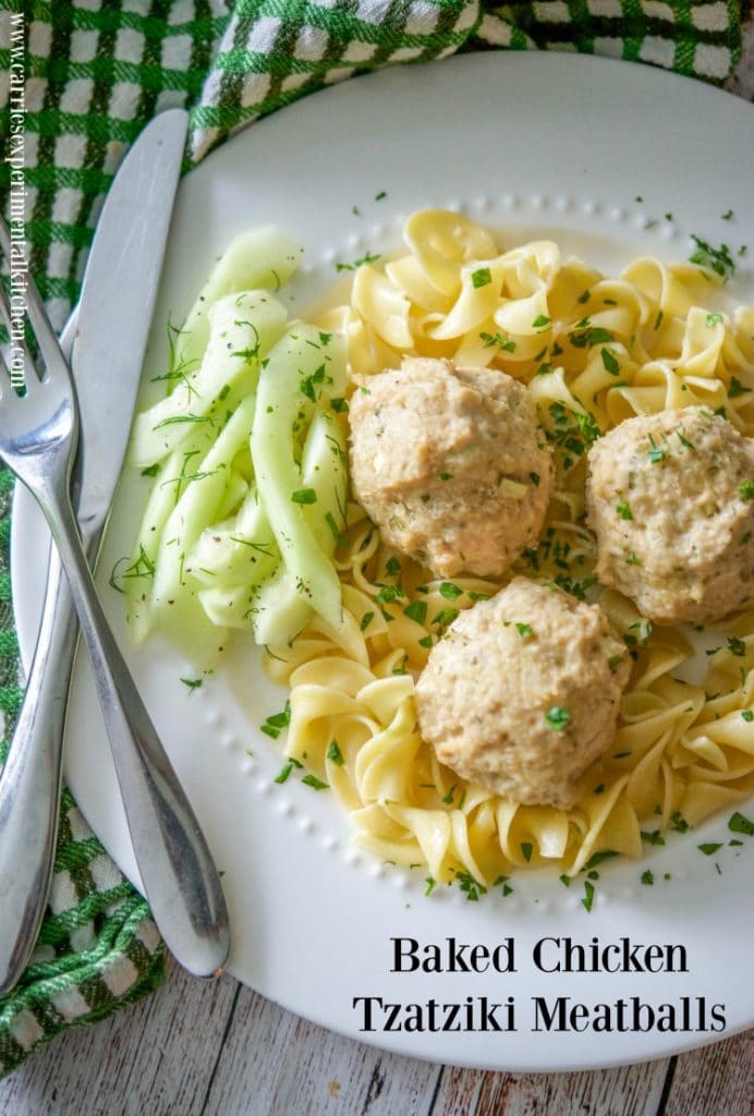 Baked Chicken Tzatziki Meatballs over egg noodles on a plate with a fork and knife. 