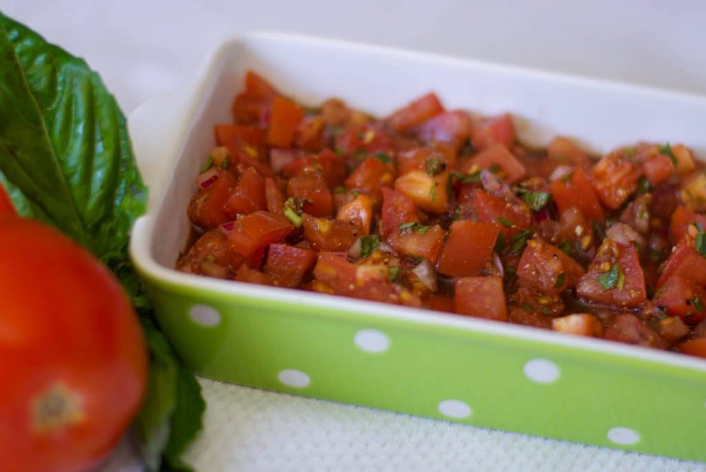 A green and white dish filled with bruschetta.