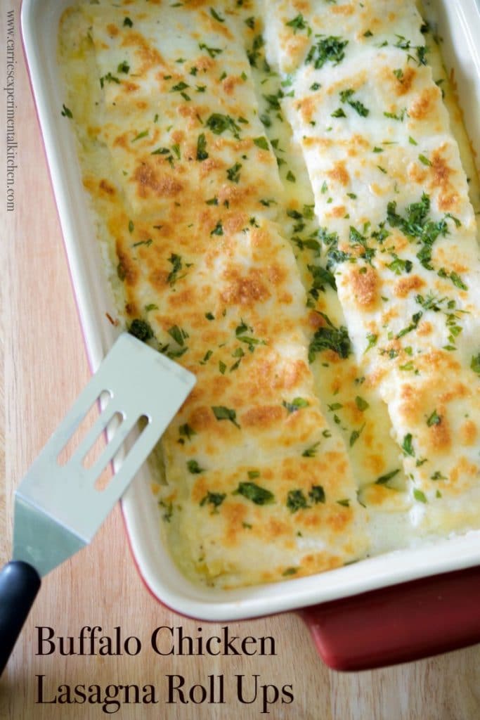 Buffalo Chicken Lasagna Roll Ups in casserole dish with a small spatula. 