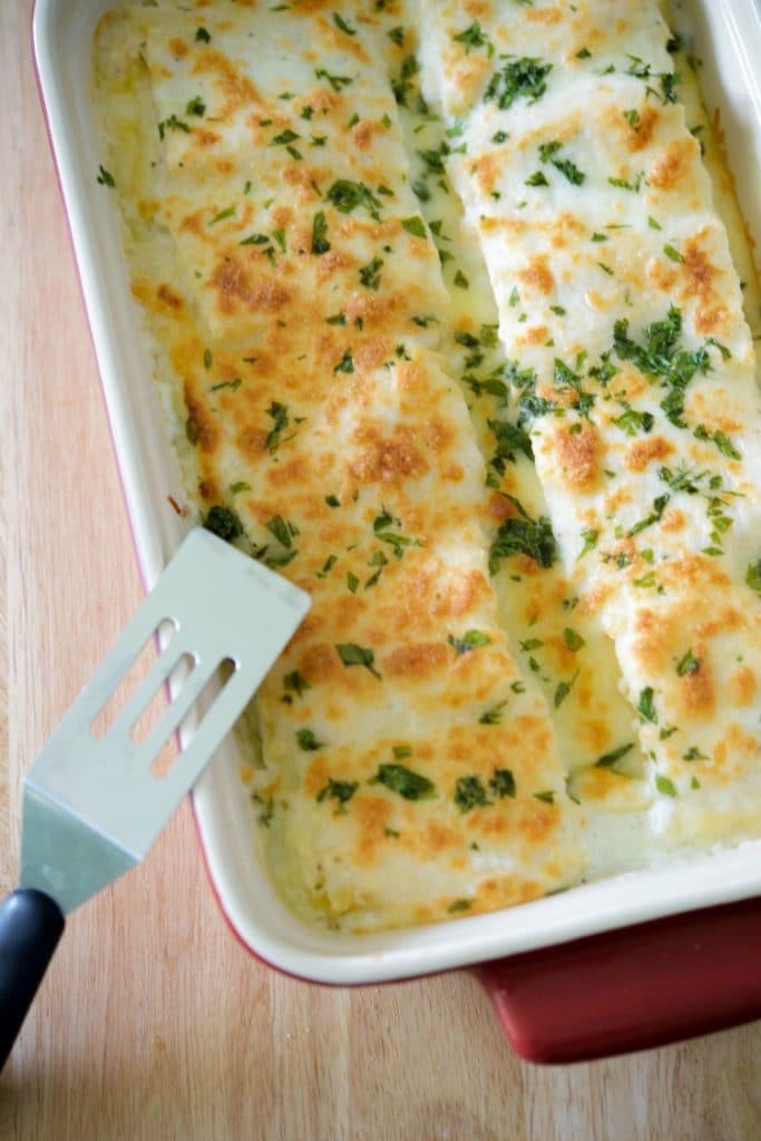 Buffalo Chicken Roll ups in a casserole dish on a wooden table. 